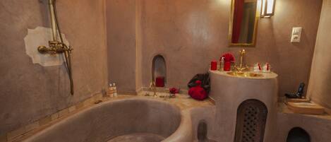 A bathroom with a large bathtub, a sink, and a mirror.