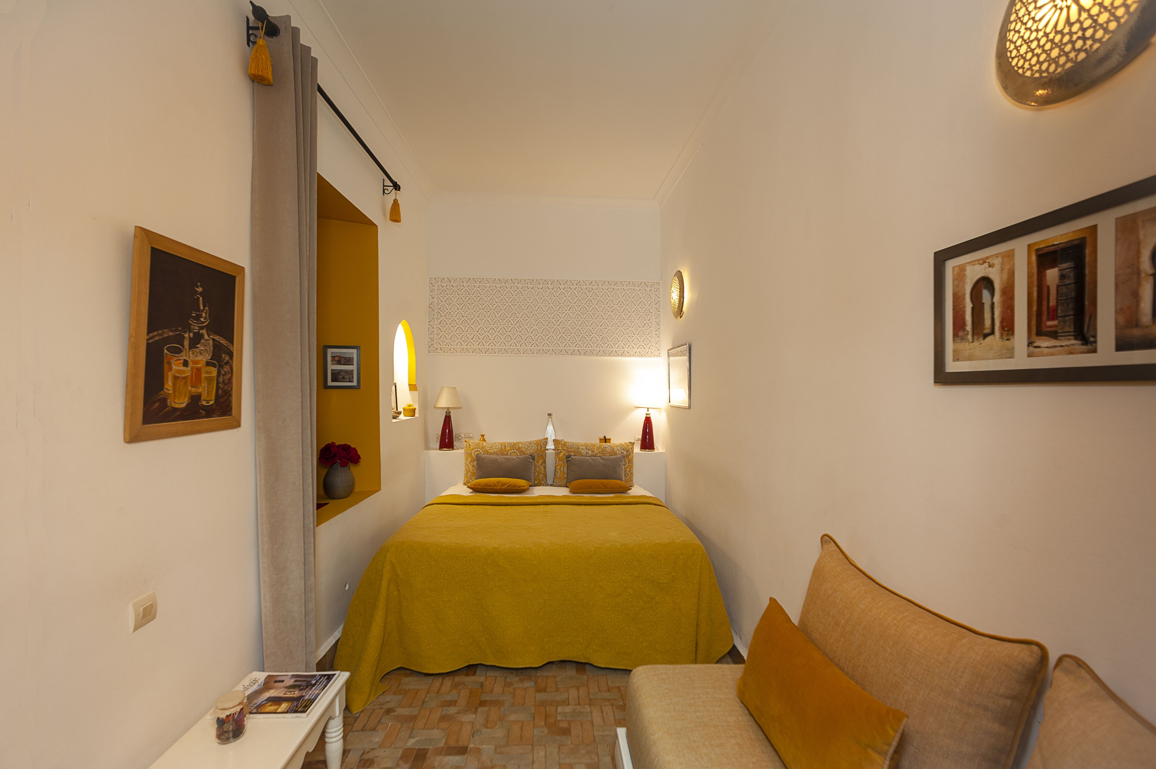 Una habitación de hotel con cama, sofá, una mesita y una pared decorada con marcos.