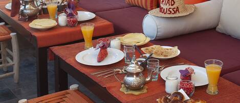 A breakfast setup with a table, plates, glasses, and a teapot.