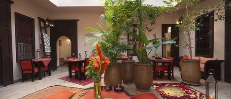 Un comedor con mesas, sillas y una decoración central que incluye un jarrón con flores.