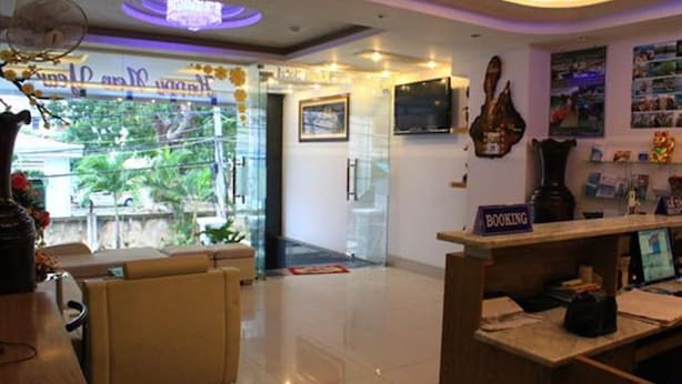 A hotel reception area with a booking counter, a television, and a guitar on the wall. - Remi hotel (Nha Trang)