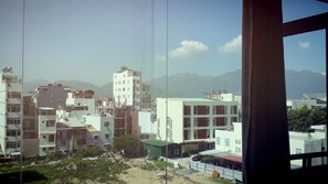 A view of a cityscape with buildings, mountains, and a clear sky.