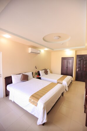 A hotel room with two beds, a wooden wardrobe, a door, and an air conditioning unit.