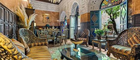 An ornately decorated interior with traditional furniture, a glass coffee table, and a large stained glass window.