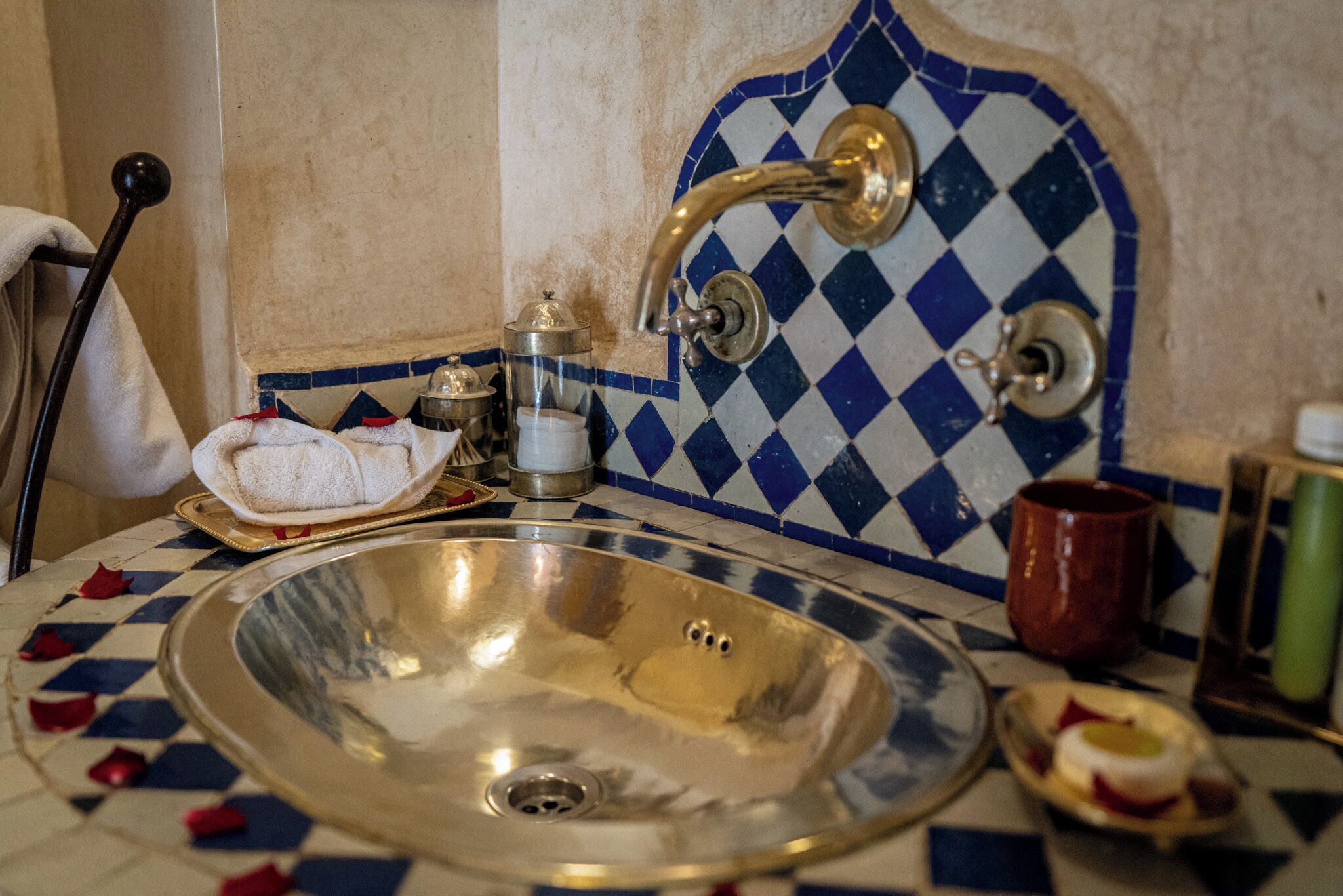 A bathroom with a large sink, a towel rack, and a decorative tiled wall.