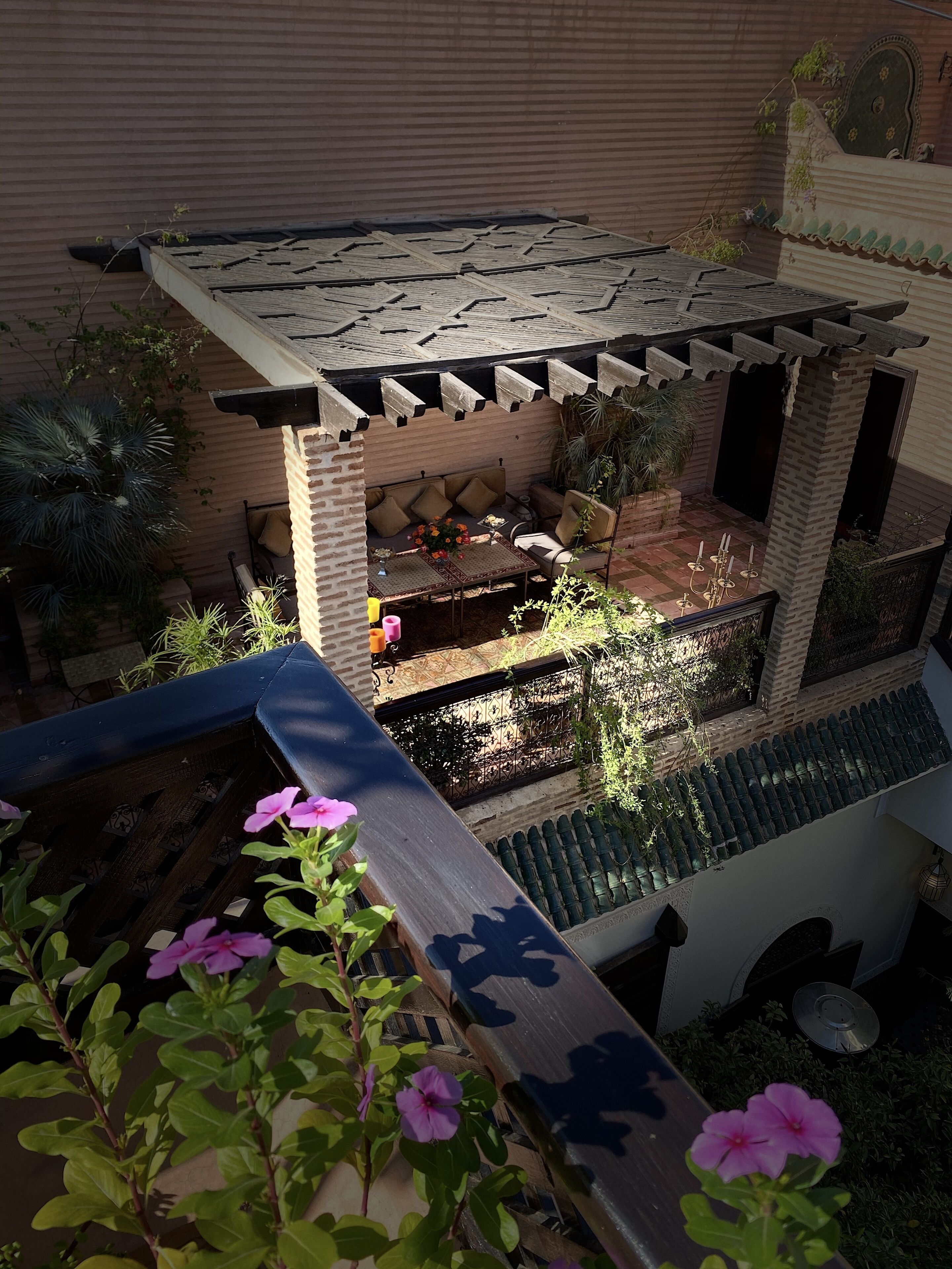 A patio area with a brick wall, a pergola, and a seating arrangement.