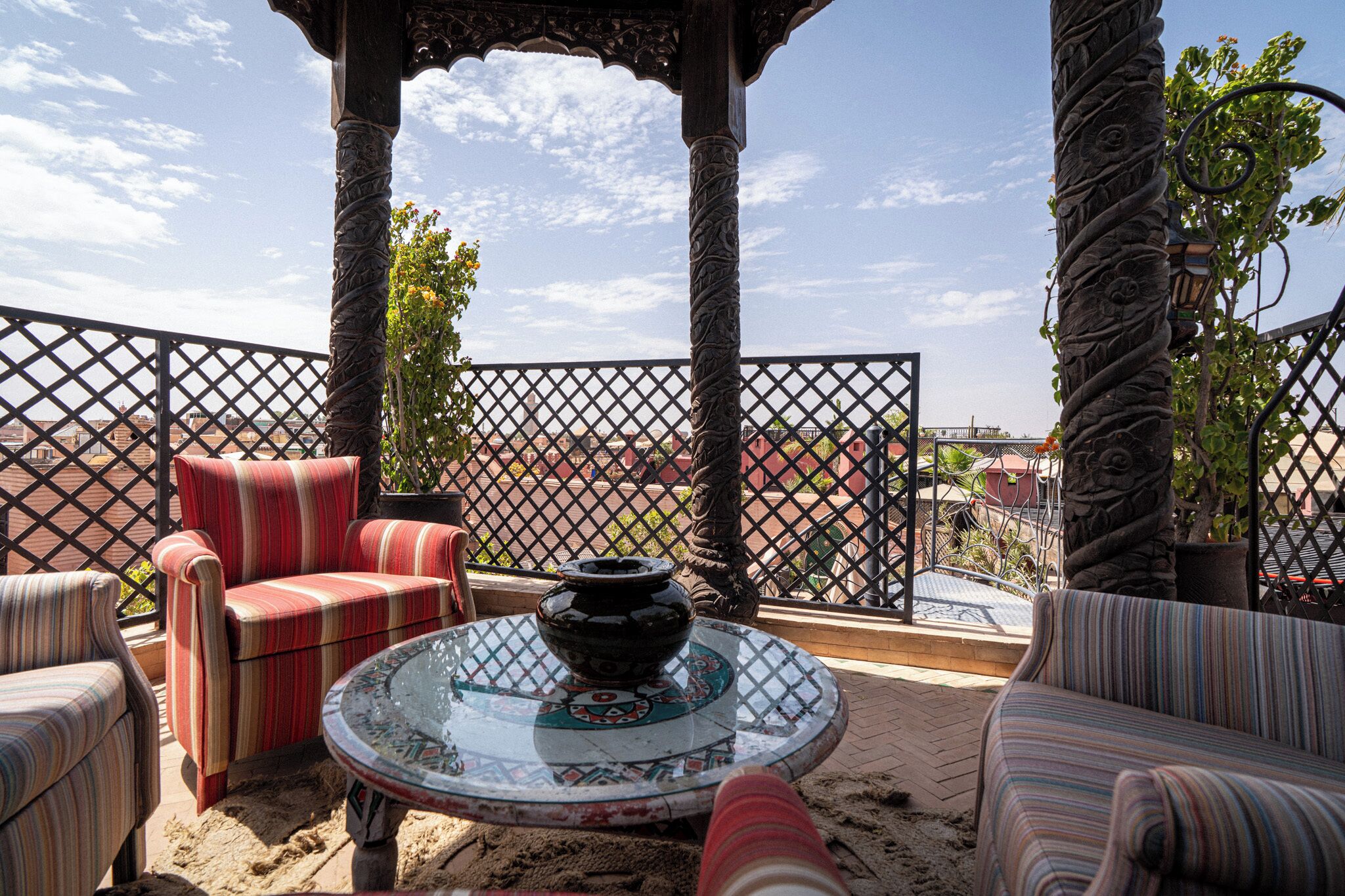 A terrace with a view of a bridge, featuring a gazebo, striped sofas, and a decorative table.