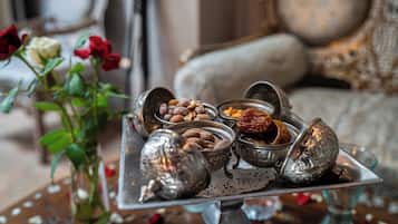 Una bandeja con frutos secos y frutas deshidratadas, un florero con rosas y un cuenco decorativo de metal.