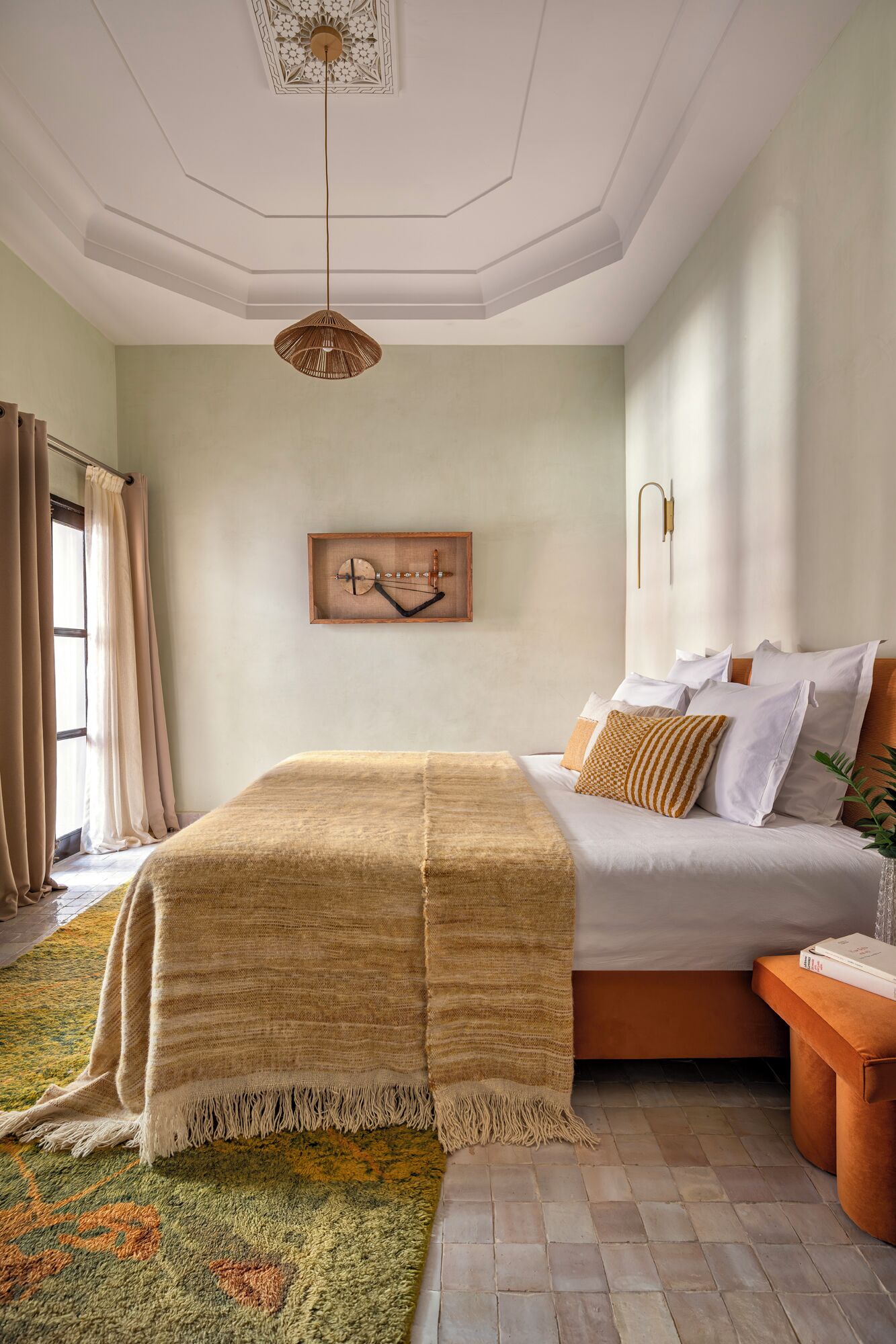 Un dormitorio con cama, lámpara colgante, reloj de pared y ventana con cortinas.