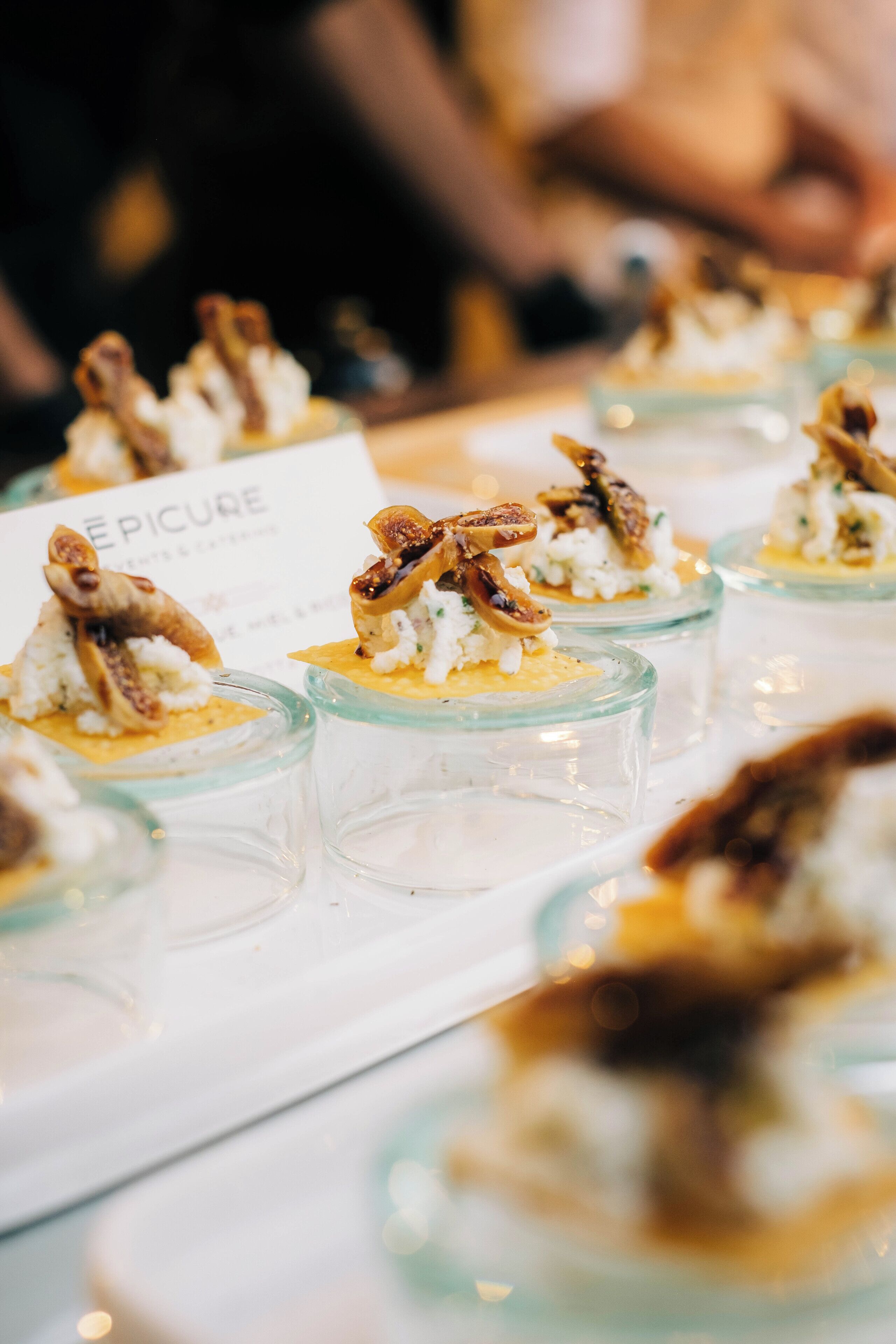 A table with glass dessert cups, each topped with a piece of fruit and nuts.