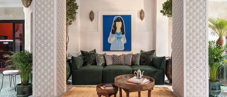 A cozy living room with a green sofa, patterned cushions, a coffee table, and a painting on the wall.