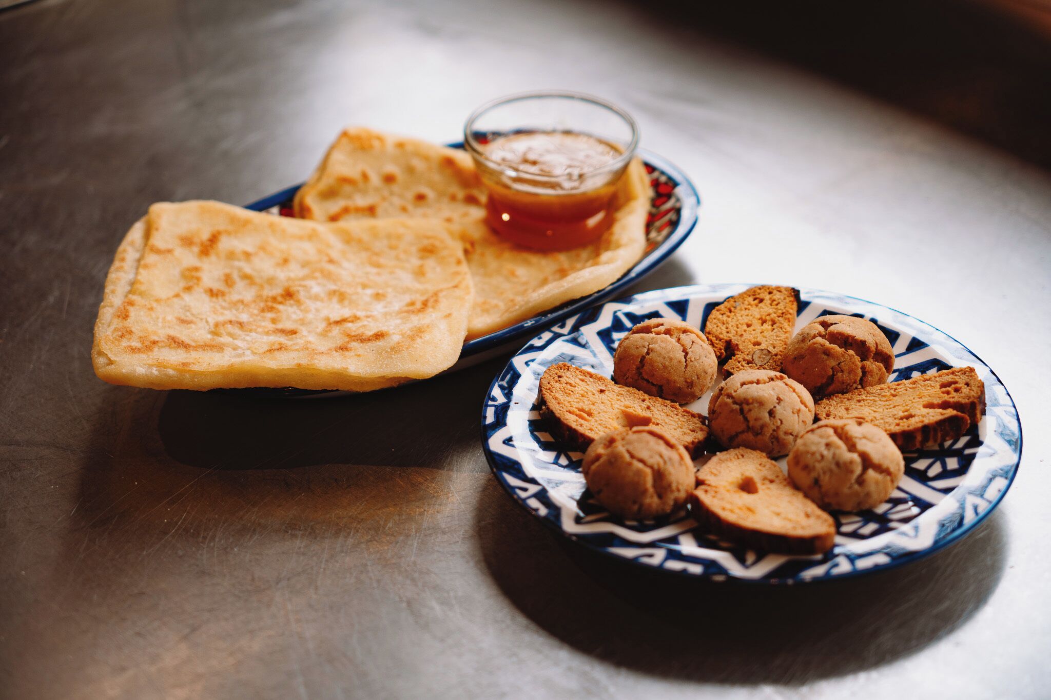 Un plato de panes planos y galletas con un recipiente pequeño de salsa.