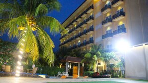 Un hôtel à plusieurs étages doté de balcons, d’un espace piscine et de palmiers.