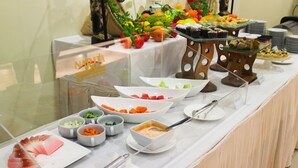Une table de buffet garnie de divers plats et sur laquelle est affiché un panneau indiquant « NARITA ».