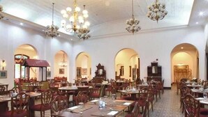 A spacious dining area with multiple tables and chairs, chandeliers, and arched doorways. - Kresna (Wonosobo)