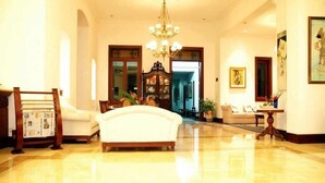 A spacious lobby with a chandelier, a white sofa, and a wooden chair. - Kresna (Wonosobo)