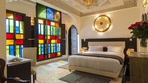 Un dormitorio espacioso con una cama grande, un escritorio y un ventanal con vidrieras de colores.