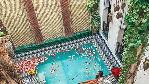 Una piscina interior con suelo de baldosas y una persona relajándose junto a la piscina.