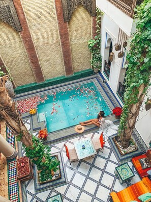 An indoor swimming pool with a tiled floor and a person relaxing by the pool.