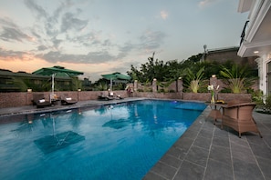 A swimming pool with lounge chairs and umbrellas, surrounded by brick walls and greenery. - Tam Coc Nam Hoa Hotel and Spa (Nam Hoa Lu)