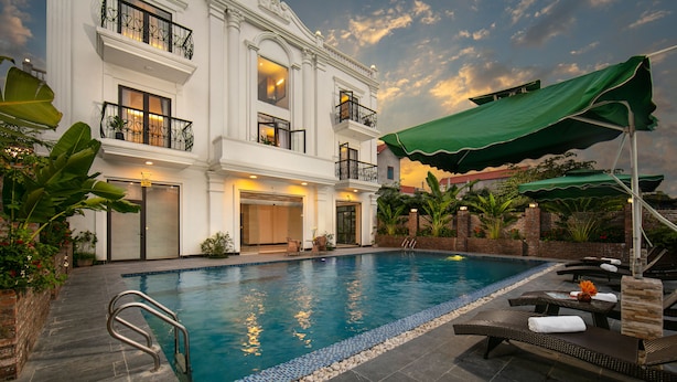A swimming pool with lounge chairs and umbrellas, surrounded by a brick wall and greenery. - Tam Coc Nam Hoa Hotel and Spa (Nam Hoa Lu)