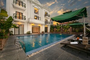 A swimming pool with lounge chairs and umbrellas, surrounded by a brick wall and greenery. - Tam Coc Nam Hoa Hotel and Spa (Nam Hoa Lu)