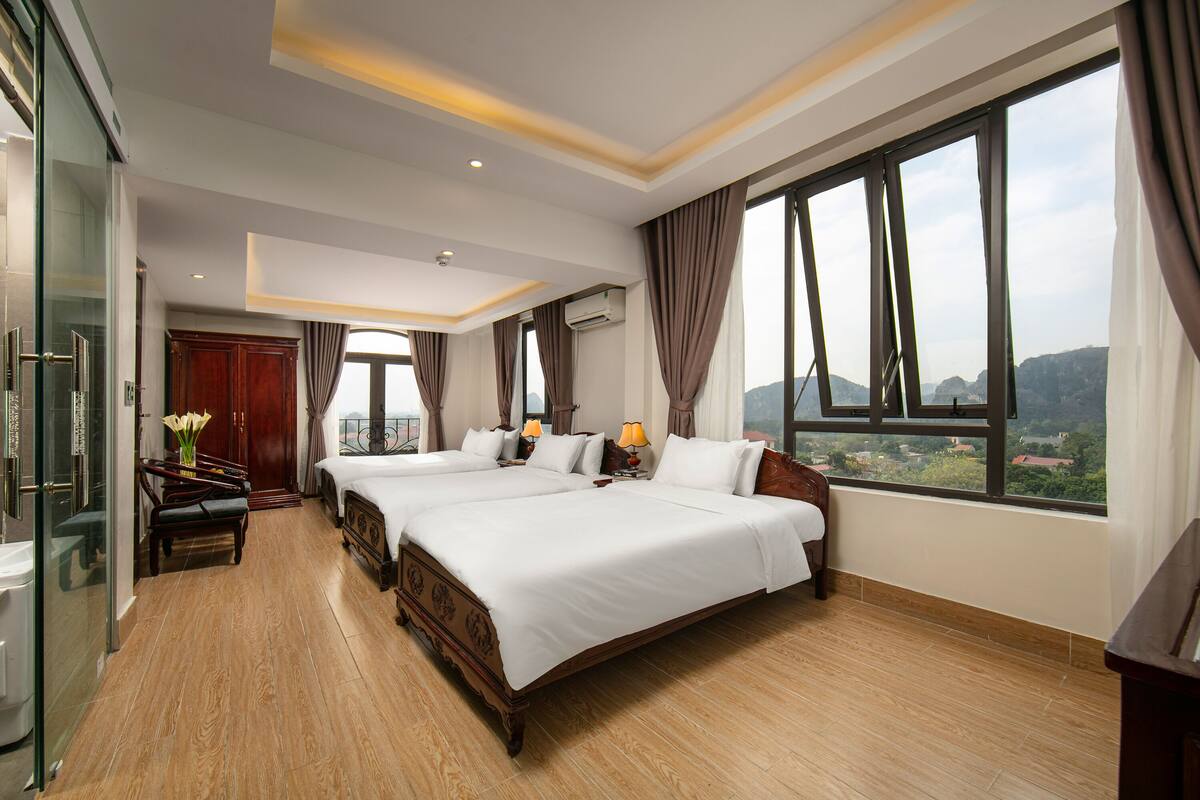 A hotel room with two beds, a desk, and a view of the city.