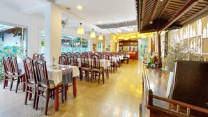 Un restaurante con filas de sillas y mesas de madera, una zona de bar y vistas al exterior a través de amplios ventanales.