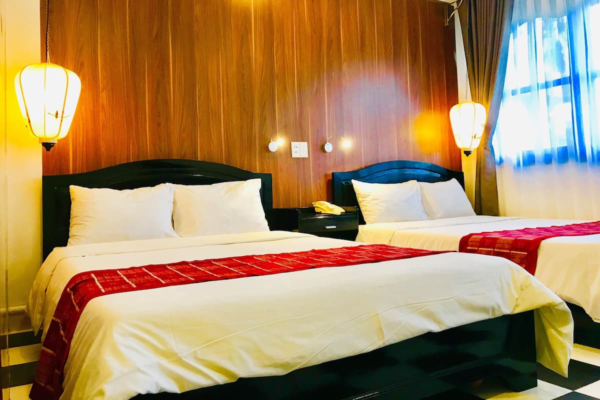Een hotelkamer met twee bedden, houten lambrisering en twee wandlampen.