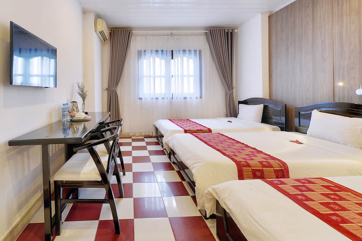 Een hotelkamer met twee bedden, een bureau en een televisie.