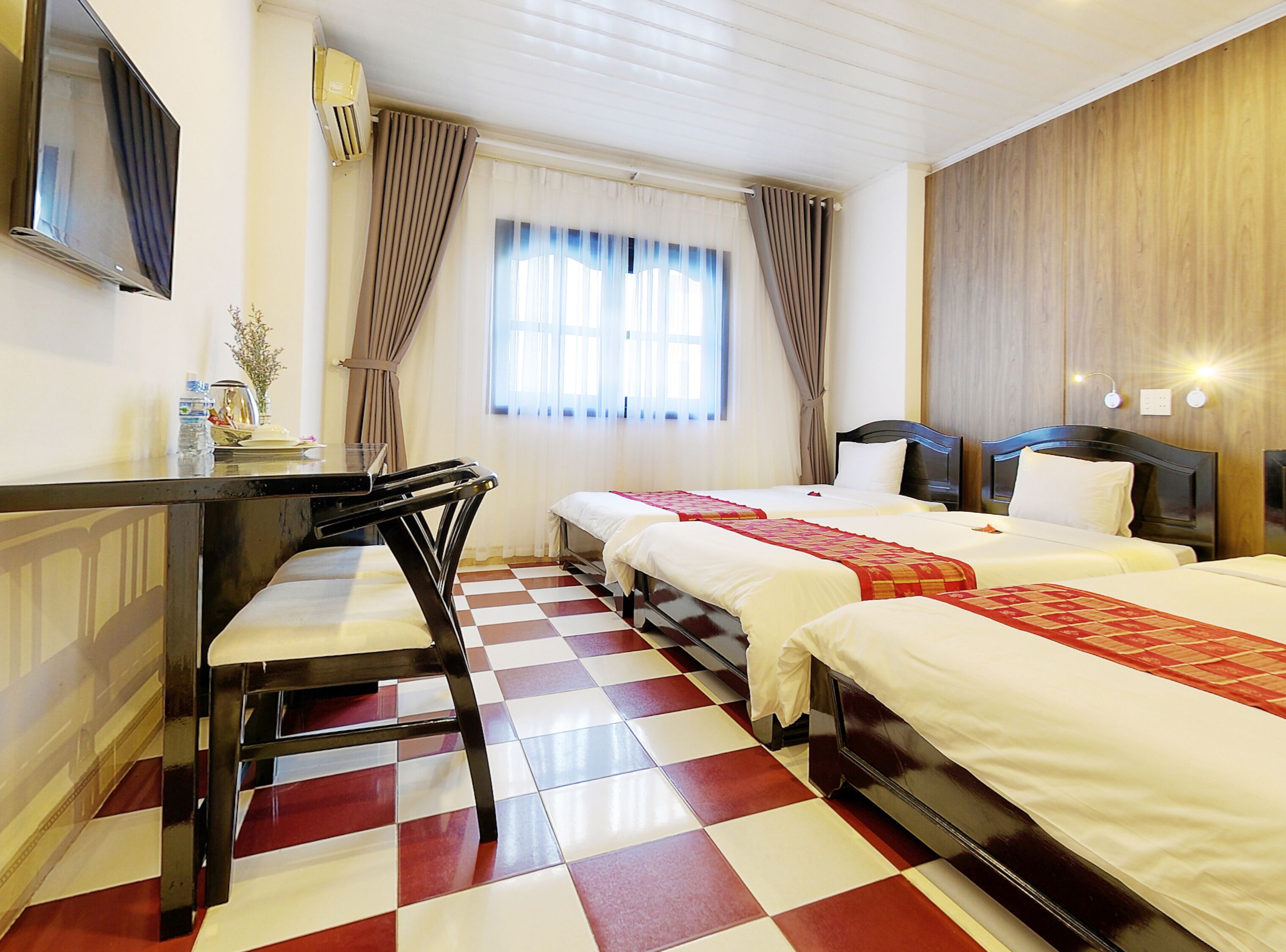 A hotel room with two beds, a desk, and a chair.