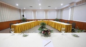 Una sala de conferències amb una taula llarga, cadires i una peça central floral.