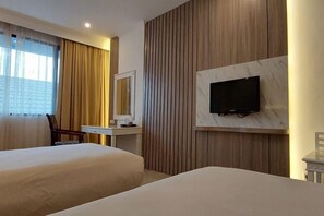 A hotel room with two beds, a desk, a chair, a television mounted on the wall, and a window with curtains. - Banjarmasin Internasional (Banjarmasin)