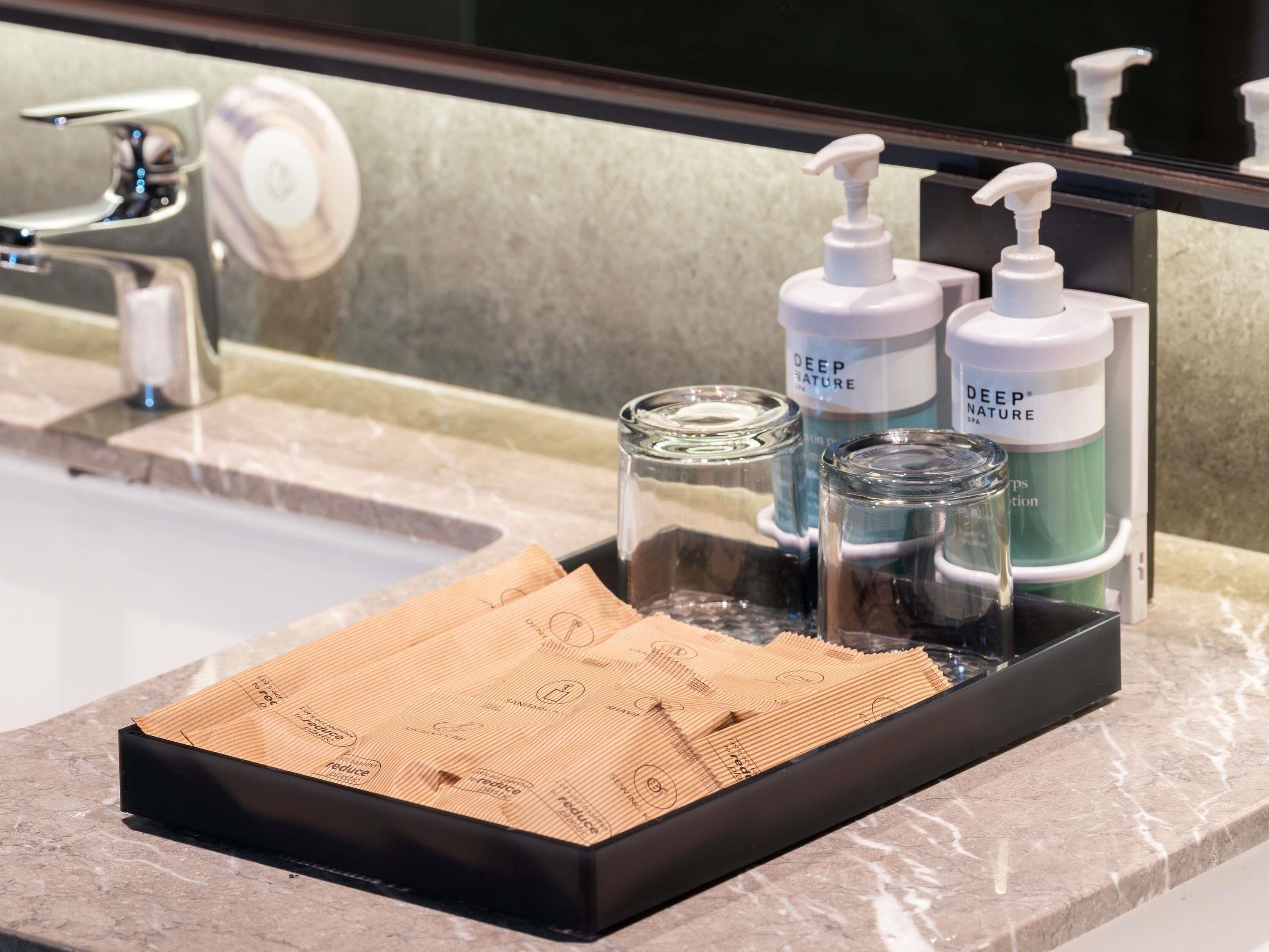 Un lavabo amb un sabater negre, dues ampolles de productes Deep Nature i un bocal de vidre.