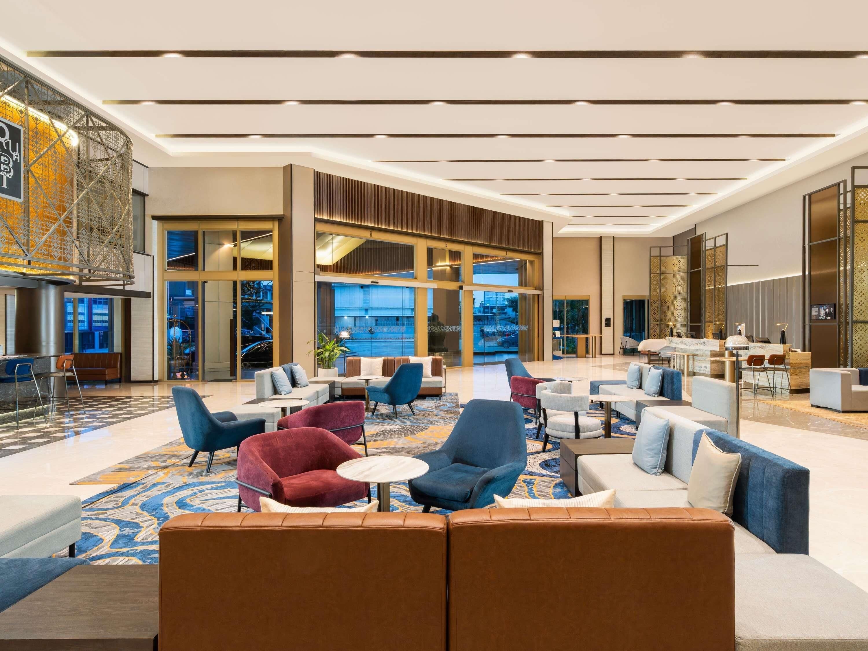A spacious lobby with modern seating, a reception desk, and large windows offering views.