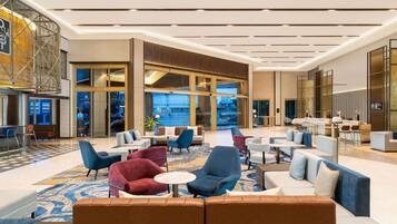 A spacious lobby with modern seating, a reception desk, and large windows offering views.