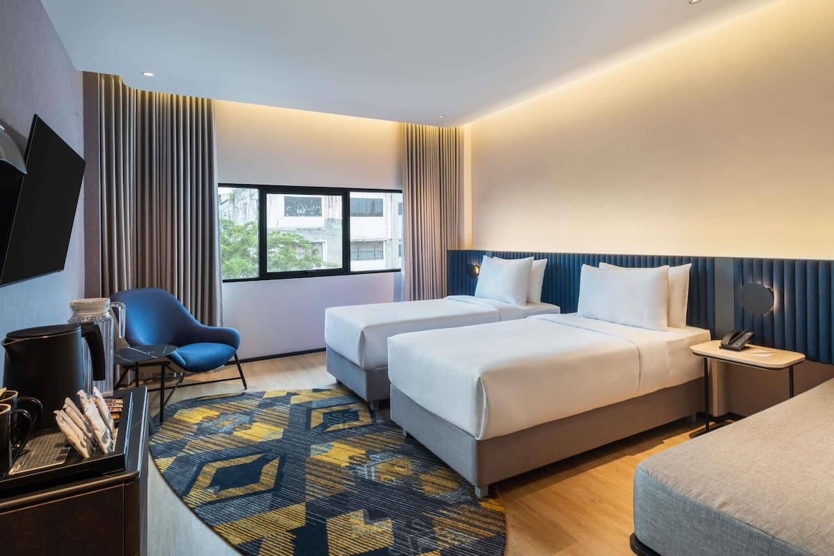 Een hotelkamer met twee bedden, een bureau, een stoel, een televisie en een raam met uitzicht.