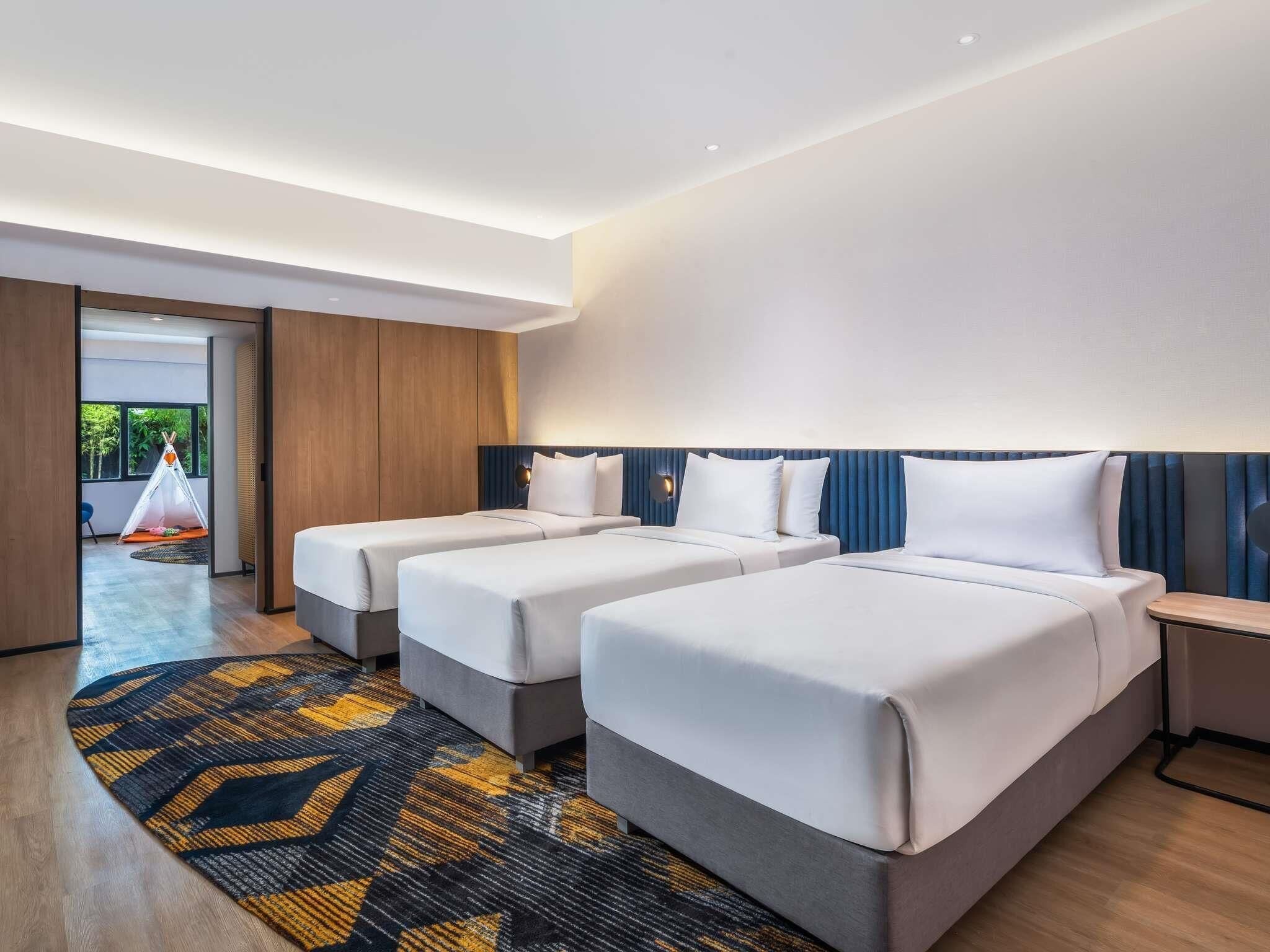 Een hotelkamer met twee bedden, een groot raam en uitzicht op de omgeving.