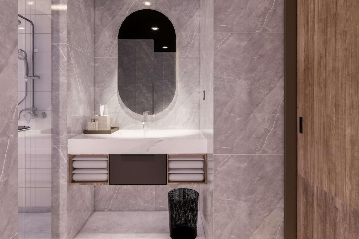 Une salle de bain moderne avec un meuble-lavabo en marbre, un grand miroir et un espace douche.