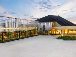 A modern hotel with a spacious courtyard, a glass facade, and a well-lit entrance. - Novotel Pontianak Convention Centre (Pontianak)