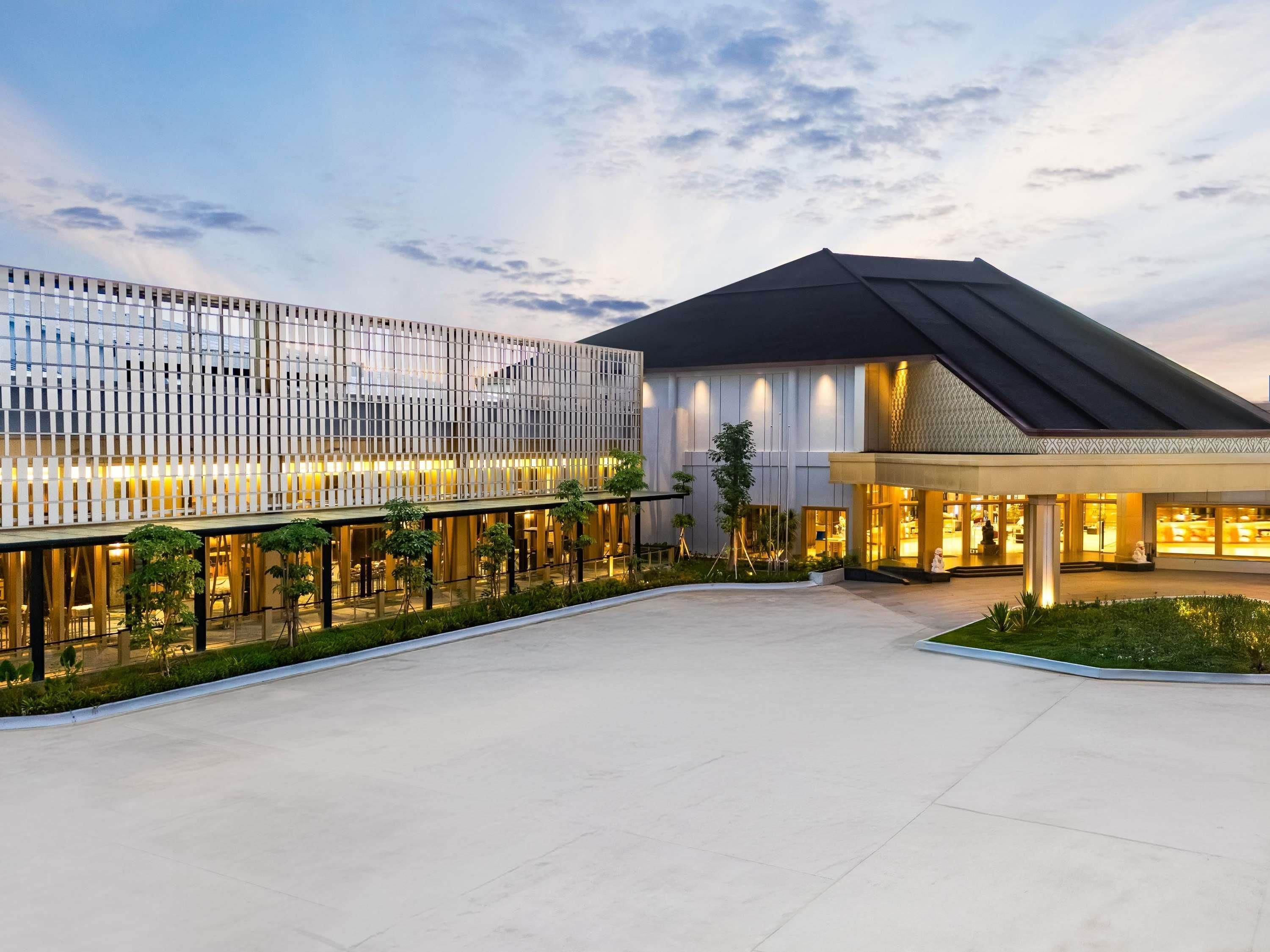 A modern hotel with a spacious courtyard, a glass facade, and a well-lit entrance.