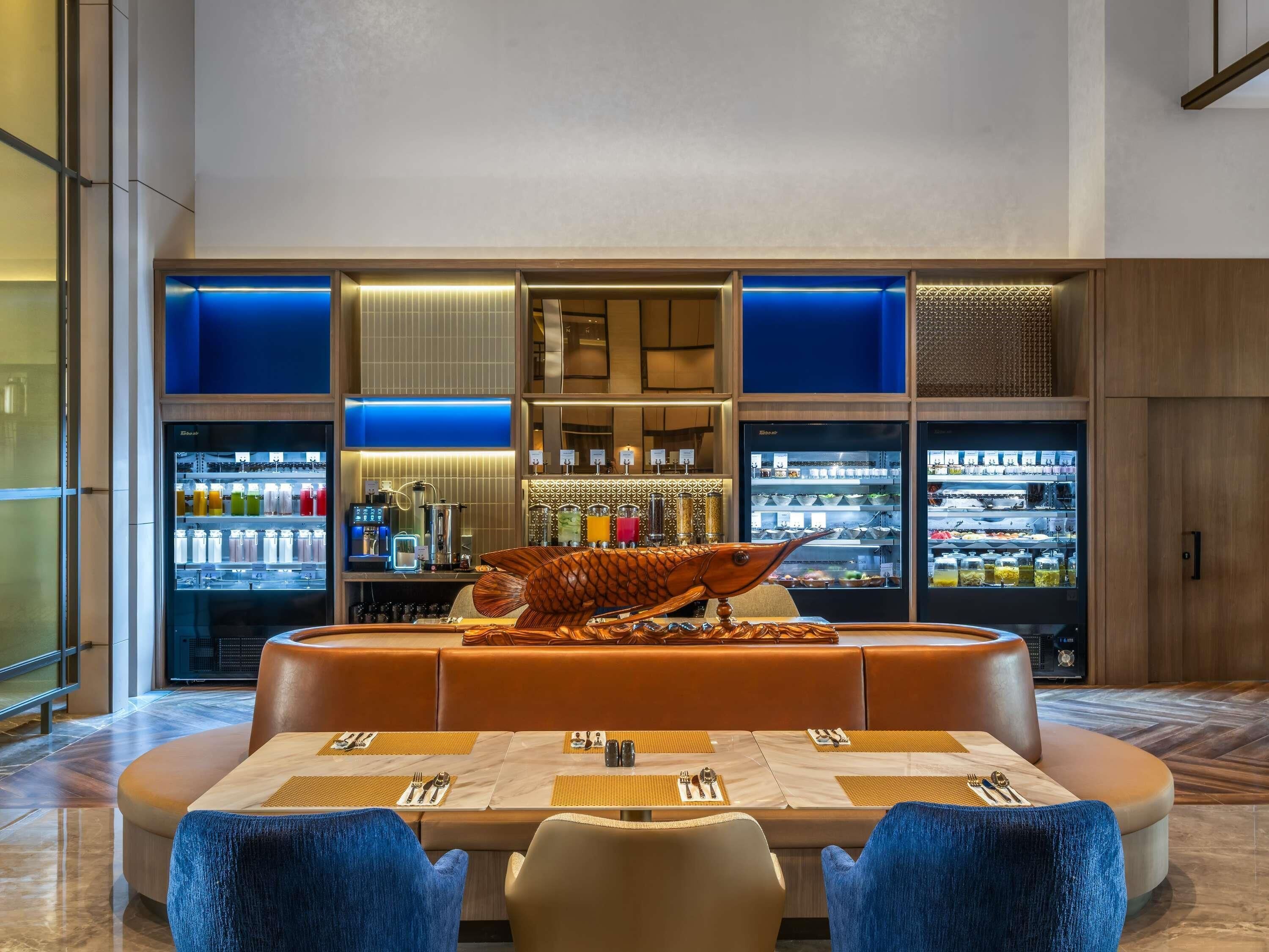 Un restaurant moderne doté d’un bar, de tables dressées et d’une sculpture de poisson décorative.
