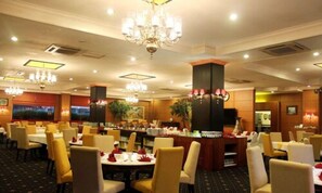 Un comedor de hotel con varias mesas y sillas, candelabros y una zona de bar.