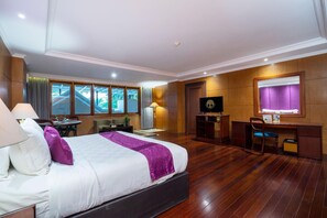 Habitación de hotel con una cama grande, un escritorio, una silla, un televisor y una ventana con cortinas.