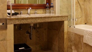A bathroom with a marble floor, a sink with a mirror, a shower enclosure, and a towel rack. - Bumi Senyiur (Samarinda)