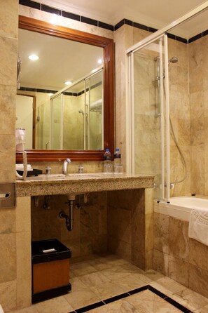 Un baño con suelo de mármol, un lavabo con espejo, cabina de ducha y un perchero para toallas.