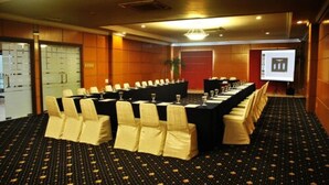 Un salón de conferencias con una larga mesa, sillas y una pantalla de proyector.