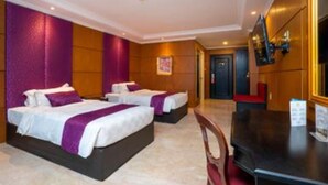 A hotel room with two beds, a desk, and a TV. - Bumi Senyiur (Samarinda)