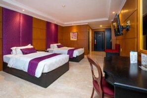 Habitación de hotel con dos camas, un escritorio y una televisión.