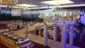 Un salón de banquetes con mesas redondas, centros de mesa florales y una araña.